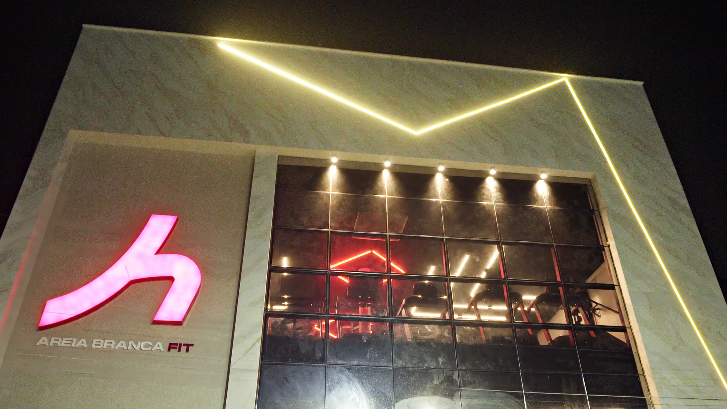 Fachada da Areia Branca Fit com o logo aceso e o contorno de LED